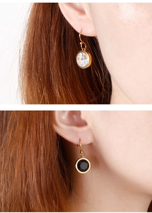Detail showing gold earrings with round-cut clear and black crystals on a model
