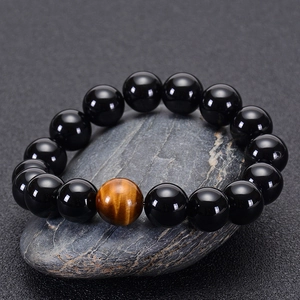 Natural black agate and tiger eye stone bead bracelet displayed on a textured grey rock