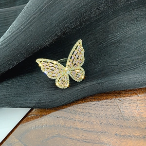 Close-up of golden butterfly ring with pink zircon gemstone and pavé crystal wings