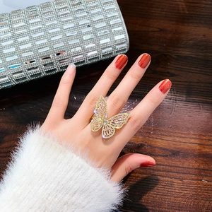 Close-up of a luxury butterfly ring with colorful zircons worn on a hand by a clutch bag