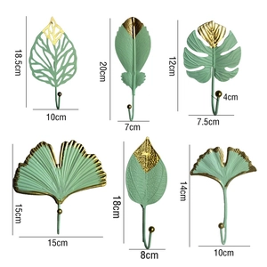 Detail of leaf-shaped metal wall hooks showing precise dimensions in green and gold finish