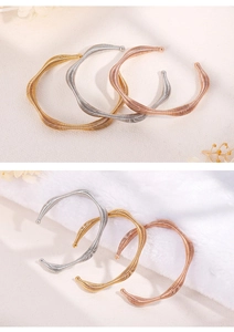Detail of twisted spiral spring bracelets in gold, silver, and rose gold wave textures