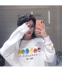 Detail view of stylish leopard print beret paired with a white M&M's graphic sweatshirt