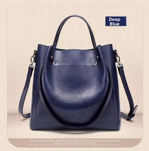 Detailed macro view of dark blue pebbled leather bucket bag with silver metal hardware