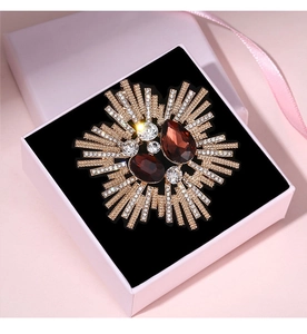 Macro shot of a vintage flower brooch with red stones in a pink gift jewelry box