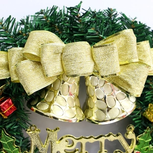 Couronne de Noël avec nœud doré, cloches et signe Merry sur des aiguilles de pin vert