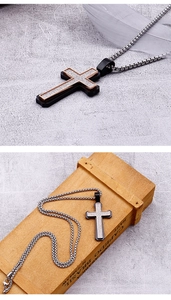Macro view of two-tone cross pendant with silver glitter inlay on a steel box chain