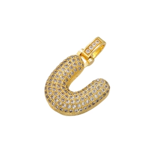 Detailed macro view of a gold plated letter U pendant with iced out cubic zirconia stones