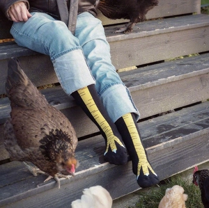 Funny chicken feet patterned over-the-knee socks worn by a model on wooden steps