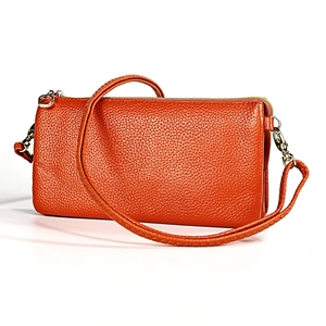 Close-up of bright orange litchi grain leather shoulder bag with golden zipper hardware