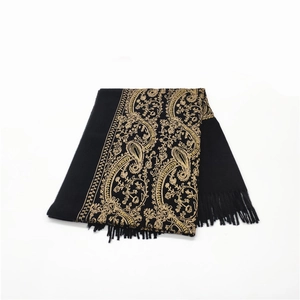 Detailed view of heavy black shawl featuring golden paisley embroidery and tassel trim