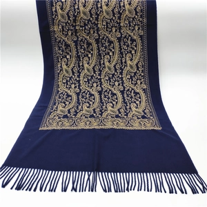 Detail of dark blue scarf featuring gold paisley embroidery and elegant fringed edges