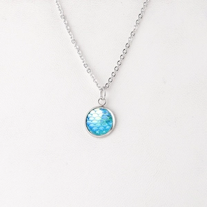 Detail of silver chain necklace with a blue mermaid fish scale round pendant charm