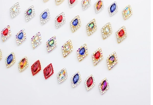 Macro view of multi-color rhombus nail art crystals with marquise stones and gold plating