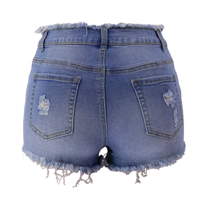Detail of high waisted blue denim shorts featuring distressed back pockets and frayed hem