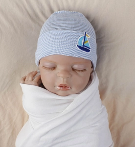 Detail of baby knitted hat with blue white stripes and sailboat embroidery