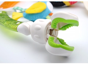 Detail of a white and green plastic stroller clip with soft silicone teeth for baby toys