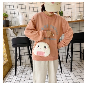 Detail of cute plush rice ball bag with metal chain strap worn on a stylish model