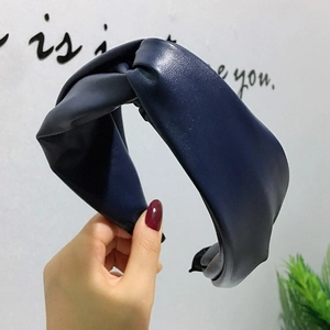 Détail d'un serre-tête en cuir PU bleu marine avec nœud croisé large et texture raffinée
