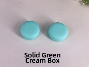 Macro close-up of two green macaron-shaped cosmetic cream jars for travel storage