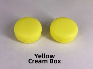 Macro view of macaron-shaped yellow plastic cream jars for cosmetic sample packaging
