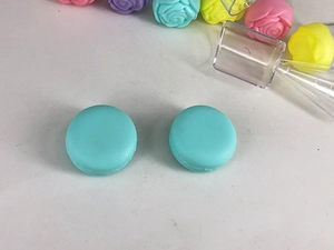 Detail of teal macaron cream jars with a plastic spatula for cosmetic packaging