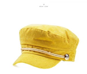 Detailed texture of yellow corduroy newsboy hat with braided rope and gold button accents