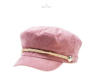 Pink corduroy newsboy cap detail with golden decorative rope and metallic side button