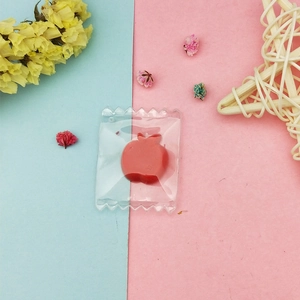 Detail of red apple resin pendant charm packaged in a transparent serrated plastic bag