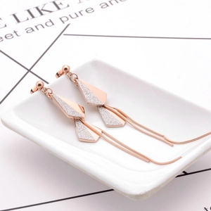 Rose gold tassel drop earrings with sparkling silver leaf charms in a ceramic dish