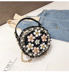 Detail of round black tweed crossbody bag with floral pearls and golden chain