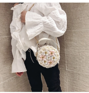 Detail of cream woven circular girls' purse with pearl strap and floral accents