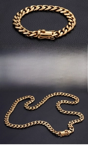 Detail of 18K gold-plated Cuban link chain with secure clasp on black leather background