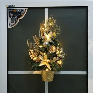 Mini green pine Christmas tree with gold ornaments and LED lights in golden base pot