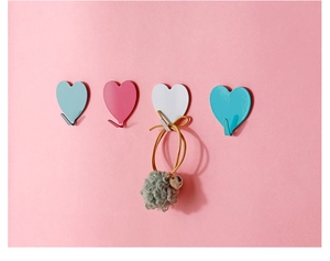 Close-up of four colorful heart-shaped hooks on a pink wall for room decoration