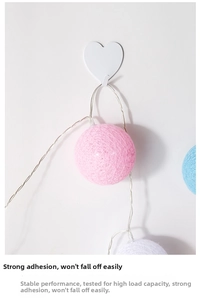 Detail of white heart-shaped adhesive hook holding colorful cotton ball string lights