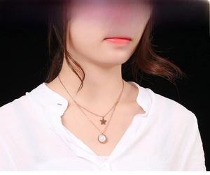 Dettaglio di una collana a due strati in oro con ciondolo a stella e perla su modella