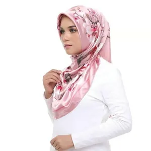 Detail of pink satin scarf with white magnolia print and smooth glossy finish texture