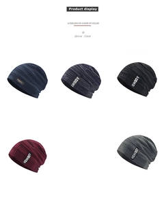 Flat lay of multiple knit beanies in navy, grey, and red with small metal logo labels