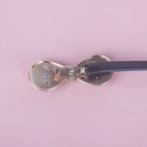 Detail of the golden bow-shaped metal buckle and black elastic band for women