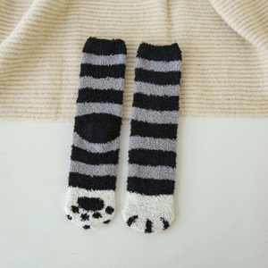 Close-up of fuzzy coral fleece socks with cat paw pattern and black striped detail