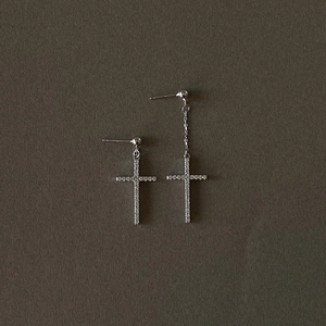 Asymmetric 925 sterling silver cross earrings with shimmering zircon pavé on dark surface
