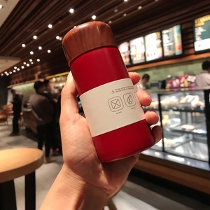 Handheld red 150ml mini insulated travel mug with wood-grain lid and matte finish texture