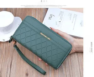 Detail of dark green quilted leather clutch with double zipper and wrist strap