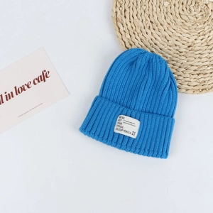 Close-up of bright blue knitted beanie featuring fine ribbed texture and woven patch label