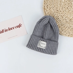 Close-up of gray ribbed knit beanie featuring vertical texture and a white woven patch tag
