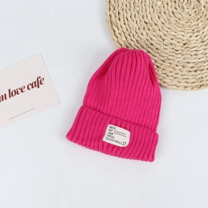 Close-up of hot pink ribbed knit beanie with white lettered woven label on a clean background