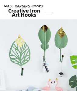 Detail of leaf-shaped metal wall hooks in dark green and gold finishes with ball tips
