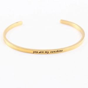 Detailed macro view of the 'you are my sunshine' engraving on a gold stainless steel bangle