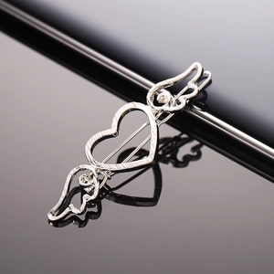 Minimalist silver metal heart wing hair clip with hollow design on black reflective surface